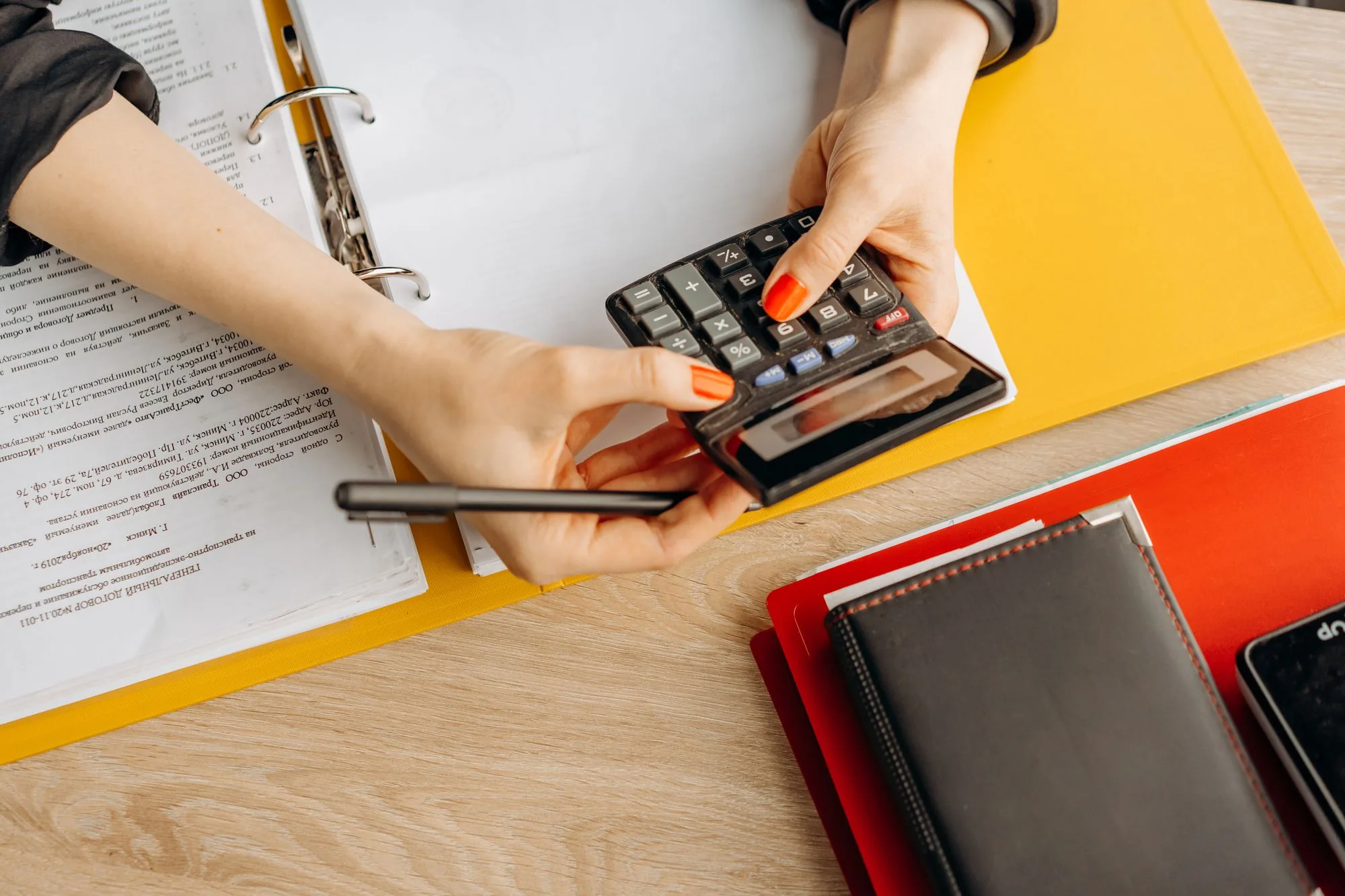 Manos usando una calculadora sobre documentos financieros en un escritorio